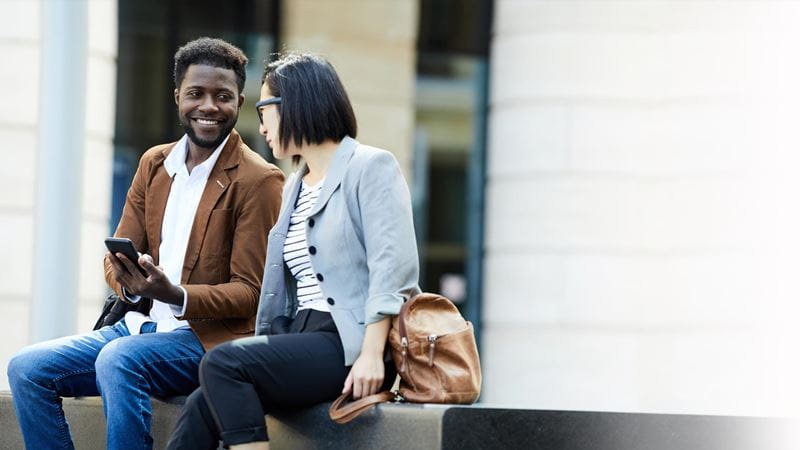 회사 밖에 앉아 이야기하는 두명의 직원